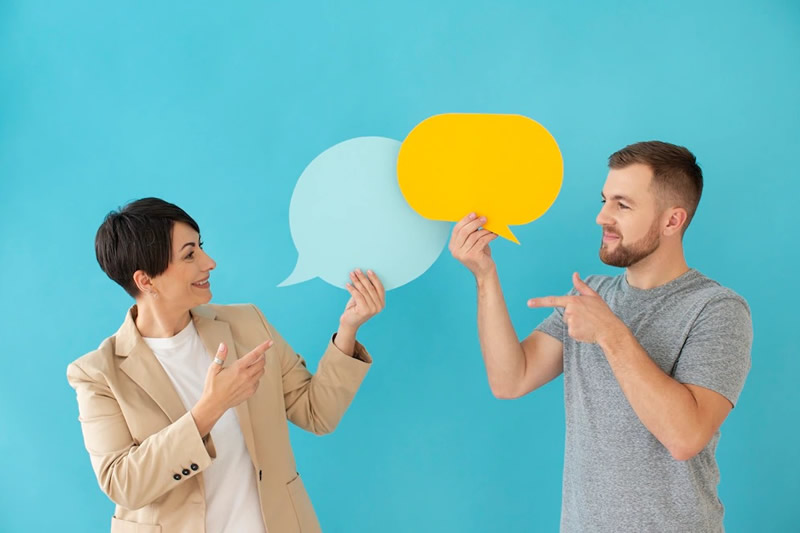Clases de inglés. Dos personas conversando, cada una sosteniento un globo de conversación.